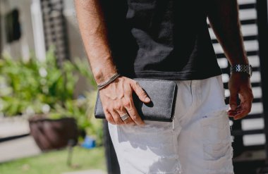 Genç işadamı cüzdanını modern evine karşı elinde tutuyor. Garajı ve arabası var..