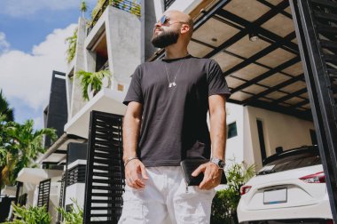 Genç işadamı garajı ve arabasıyla modern evinden çıkıyor..