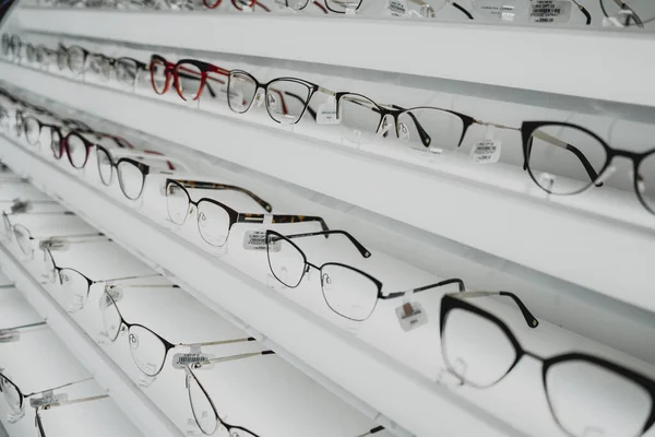 Rows of sunglasses on the counter of an optical store.