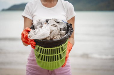Kadın bir çevre bilimci plastikten ve diğer atıklardan sahil kenarını temizliyor..