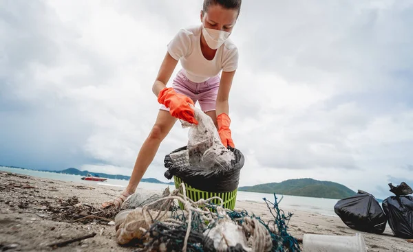 Kadın bir çevre bilimci plastikten ve diğer atıklardan sahil kenarını temizliyor..