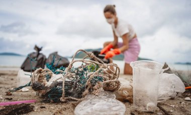 Kadın bir çevre bilimci plastikten ve diğer atıklardan sahil kenarını temizliyor..