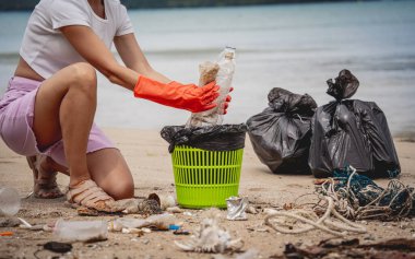 Kadın bir çevre bilimci plastikten ve diğer atıklardan sahil kenarını temizliyor..