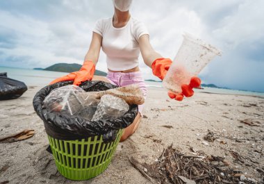 Kadın bir çevre bilimci plastikten ve diğer atıklardan sahil kenarını temizliyor..