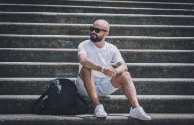 Yalnız genç yakışıklı adam parkta merdivenlerde oturuyor..