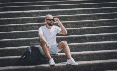 Yalnız genç yakışıklı adam parkta merdivenlerde oturuyor..