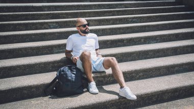 Yalnız genç yakışıklı adam parkta merdivenlerde oturuyor..