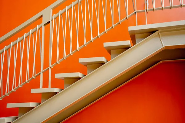 Metal stairs on the big orange wall.