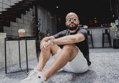 Modern şehir kafesinde tişört ve şort giyen genç bir adam..