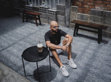 Modern şehir kafesinde tişört ve şort giyen genç bir adam..