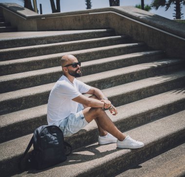 Yalnız genç yakışıklı adam parkta merdivenlerde oturuyor..