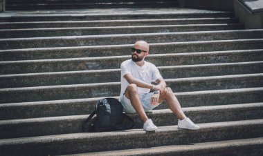 Yalnız genç yakışıklı adam parkta merdivenlerde oturuyor..