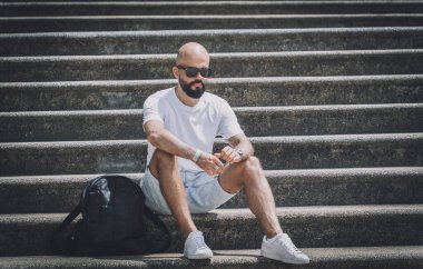 Yalnız genç yakışıklı adam parkta merdivenlerde oturuyor..