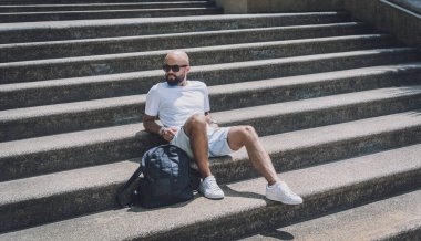 Yalnız genç yakışıklı adam parkta merdivenlerde oturuyor..