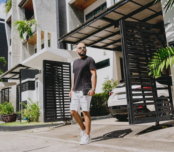 Genç işadamı garajı ve arabasıyla modern evinden çıkıyor..