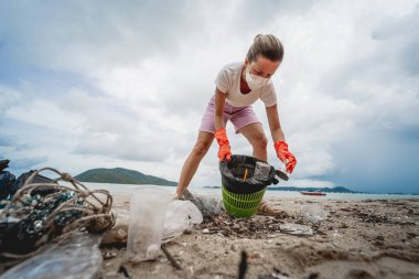 Kadın bir çevre bilimci plastikten ve diğer atıklardan sahil kenarını temizliyor..