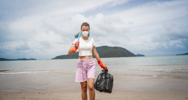 Kadın bir çevre bilimci plastikten ve diğer atıklardan sahil kenarını temizliyor..