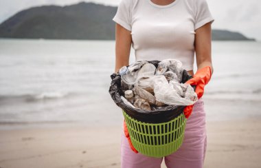 Kadın bir çevre bilimci plastikten ve diğer atıklardan sahil kenarını temizliyor..