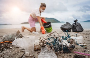 Kadın bir çevre bilimci plastikten ve diğer atıklardan sahil kenarını temizliyor..