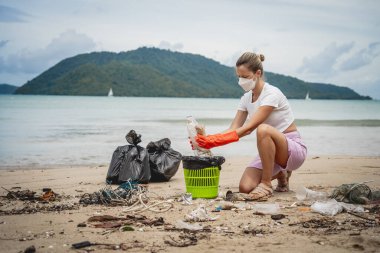 Kadın bir çevre bilimci plastikten ve diğer atıklardan sahil kenarını temizliyor..