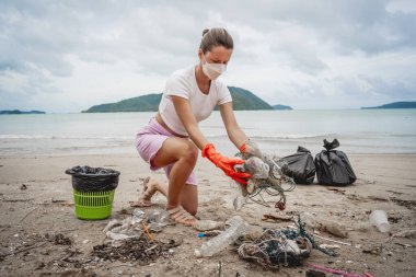 Kadın bir çevre bilimci plastikten ve diğer atıklardan sahil kenarını temizliyor..