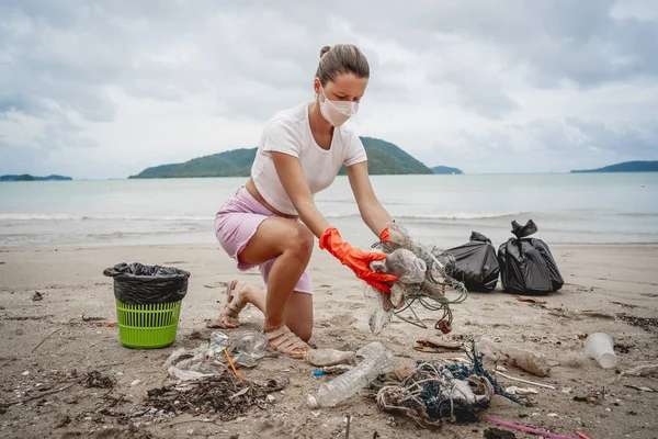 Kadın bir çevre bilimci plastikten ve diğer atıklardan sahil kenarını temizliyor..