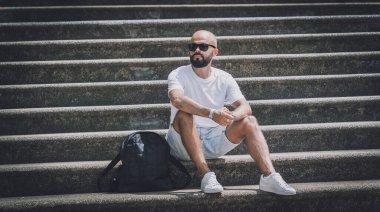 Yalnız genç yakışıklı adam parkta merdivenlerde oturuyor..