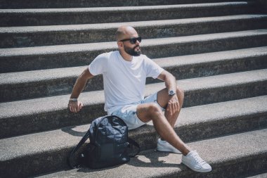 Yalnız genç yakışıklı adam parkta merdivenlerde oturuyor..