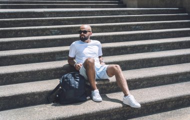 Yalnız genç yakışıklı adam parkta merdivenlerde oturuyor..