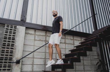 Şehrin sokaklarındaki merdivenlerde tişörtlü ve şortlu genç bir adam..