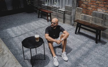 Modern şehir kafesinde tişört ve şort giyen genç bir adam..