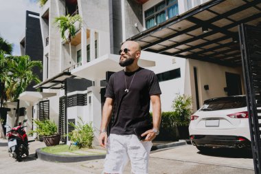 Genç işadamı garajı ve arabasıyla modern evinden çıkıyor..