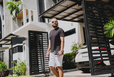 Genç işadamı garajı ve arabasıyla modern evinden çıkıyor..