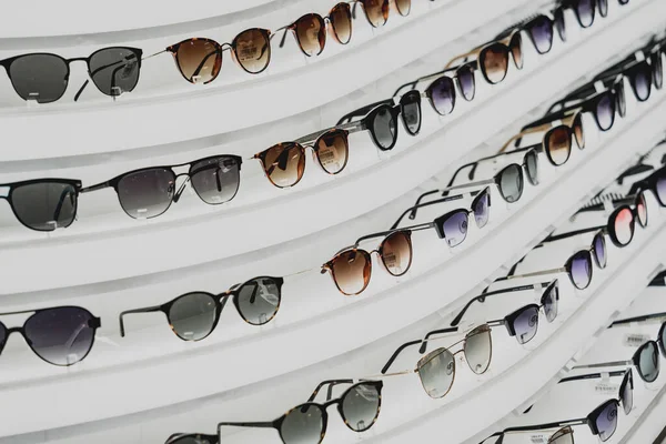 Rows of sunglasses on the counter of an optical store.