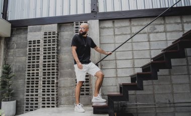 Şehrin sokaklarındaki merdivenlerde tişörtlü ve şortlu genç bir adam..