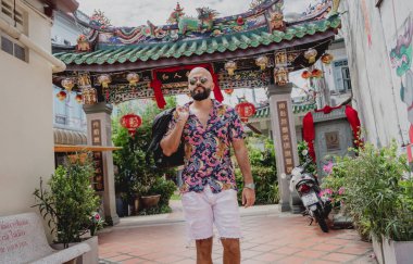 Asya tapınağının arka planında sırt çantası olan genç bir adam..