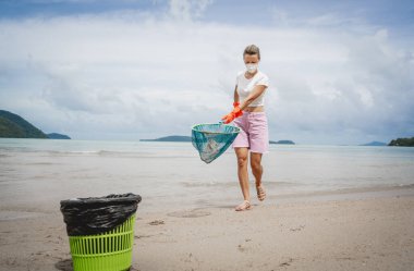 Kadın bir çevre bilimci plastikten ve diğer atıklardan sahil kenarını temizliyor..