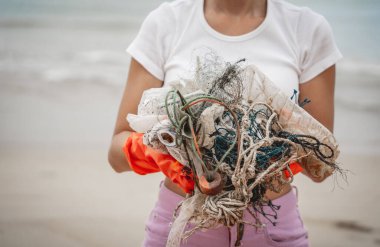 Kadın bir çevre bilimci plastikten ve diğer atıklardan sahil kenarını temizliyor..