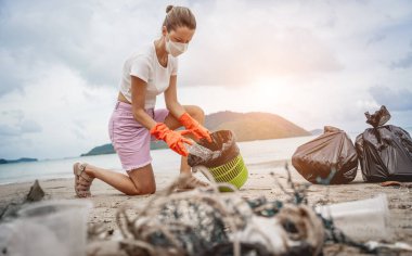 Kadın bir çevre bilimci plastikten ve diğer atıklardan sahil kenarını temizliyor..