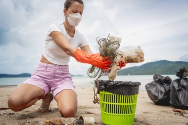 Kadın bir çevre bilimci plastikten ve diğer atıklardan sahil kenarını temizliyor..