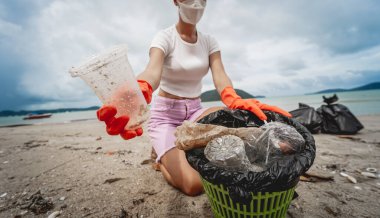 Kadın bir çevre bilimci plastikten ve diğer atıklardan sahil kenarını temizliyor..