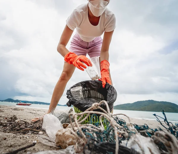 Kadın bir çevre bilimci plastikten ve diğer atıklardan sahil kenarını temizliyor..