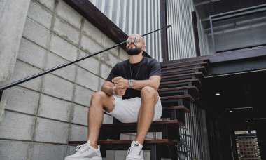 Şehrin sokaklarındaki merdivenlerde tişörtlü ve şortlu genç bir adam..