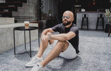 Modern şehir kafesinde tişört ve şort giyen genç bir adam..