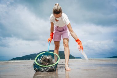 Kadın bir çevre bilimci plastikten ve diğer atıklardan sahil kenarını temizliyor..