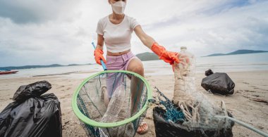 Kadın bir çevre bilimci plastikten ve diğer atıklardan sahil kenarını temizliyor..
