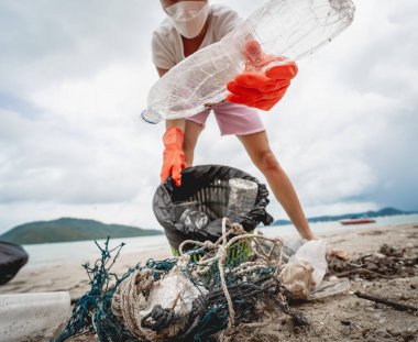 Kadın bir çevre bilimci plastikten ve diğer atıklardan sahil kenarını temizliyor..