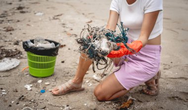 Kadın bir çevre bilimci plastikten ve diğer atıklardan sahil kenarını temizliyor..