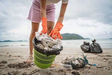 Kadın bir çevre bilimci plastikten ve diğer atıklardan sahil kenarını temizliyor..