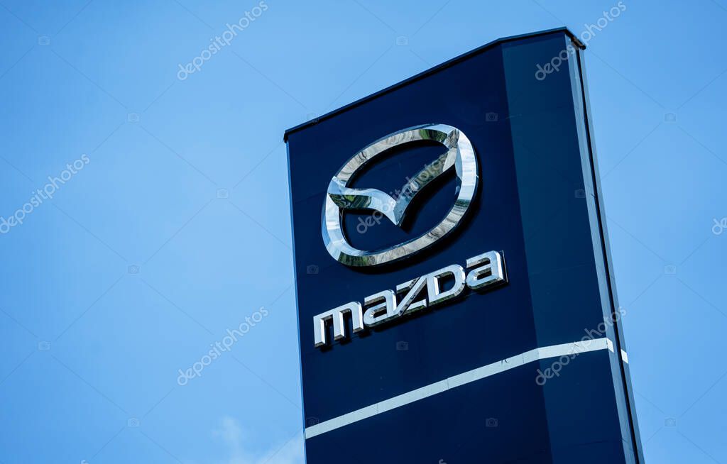 PHUKET, THAILAND - JUNE 05, 2022: Signboard with logo of Mazda Motor Corporation against blue sky.